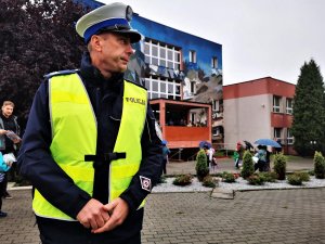 policjant drogówki w odblaskowej kamizelce, w tle budynek mikołowskiej szkoły podstawowej