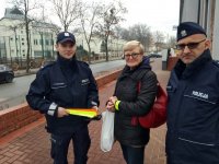 na zdjęciu: policjanci wręczają odblask starszej kobiecie, Łaziska Górne, przy budynku domu kultury