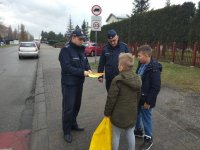 na zdjęciu: policjanci wręczają odblaski dzieciom przed budynkiem szkoły, Łaziska Górne