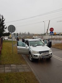 Zdjęcie kolorowe. Widoczne czynności zatrzymania i doprowadzenia mężczyzny przez policjantów