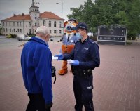 na zdjęciu: dzielnicowy wraz z policyjną maskotką rozdaje mieszkańcom maseczki ochronne