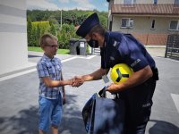 na zdjęciu: policjant gratuluje chłopcu zwycięstwa w konkursie, podaje mu rękę, Orzesze