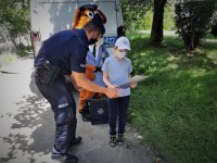 na zdjęciu: policjant wręcza dyplom i nagrodę chłopcu, w tle radiowóz oraz sierżant Hektor