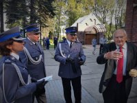 na zdjeciu widać policjantów w mundurach galowych na placu przed wejściem do kościoła, obok nich stoi starszy mężczyzna