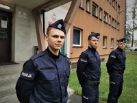 na zdjęciu widać policjantów w mundurach, którzy stoją przed budynkiem komendy