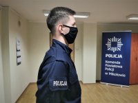 na zdjęciu widać umundurowanego policjanta podczas uroczystości ślubowania, w tle baner z logiem mikołowskiej Policji