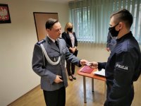 na zdjęciu: komendant wręcza policjantowi służbową legitymację, w tle - pracownik cywilny