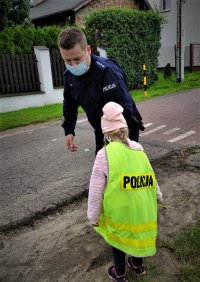 umundurowany policjant z dziewczynką w odblaskowej kamizelce