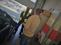 policjant ruchu drogowego rozmawia z klientem stacji diagnostycznej, w tle widać samochody stojące na parkingu