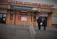 na zdjęciu policjanci stoją na schodach przed budynkiem szkoły