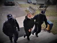 umundurowani policjanci prowadzą zatrzymaną kobietę, wchodzą po schodach do budynku komendy Policji w Mikołowie