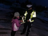 policjant drogówki wręcza dziecku odblaskową opaskę