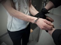 policjant zapina kajdanki zatrzymanemu mężczyźnie