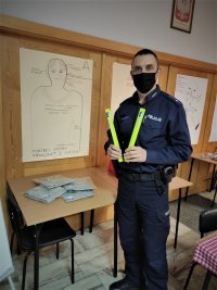 umundurowany policjant trzyma odblaskowe opaski