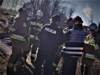 policjantka rozmawia z uczestniczącymi w akcji strażakami. W tle miejsce zabezpieczenia w Łaziskach Górnych