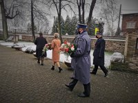 na zdjęciu widać kilka osób. Wśród nich policjanci mikołowskiej komendy niosący kwiaty. Scena ma miejsce przy kościele w Mikołowie-Bujakowie