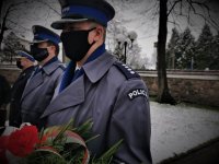 na zdjęciu widać dwóch umudnurowanych policjantów. Jeden z nich trzyma bukiet kwiatów