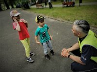 policjant ruchu drogowego kuca i rozmawia z dwojgiem dzieci