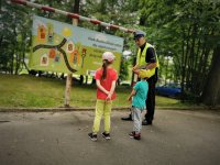 policjant ruchu drogowego wskazuje na tablicę z tutułem &amp;amp;quot; Park Ruchu Drogowego&amp;amp;quot;. Przyglądają mu się dzieci.