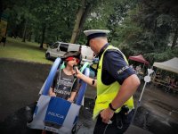 policjant ruchu drogowego zadaje pytanie dziecku. W ręce trzyma mikrofon