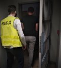 policjant w odblaskowej kamizelce prowadzi zatrzymanego mężczyznę