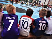 siedzący tyłem chłopcy, każdy z nich ma koszulkę wybranego sportowca - piłkarza