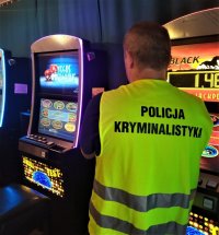 policjant w odblaskowej kamizelce stoi przed automatem do gier