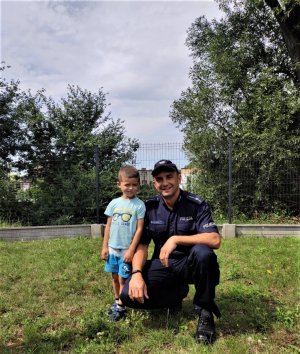 mały chłopiec pozuje do zdjęcia z policjantem