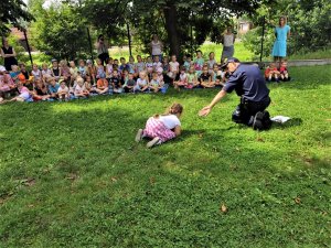 policjant prowadzi zajęcia profilaktyczne, grupa dzieci siedzi i słucha