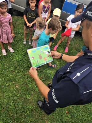 policjant trzyma w ręce pracę plastyczną dzieci