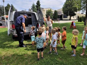 grupa małych dzieci ogląda policyjny radiowóz.