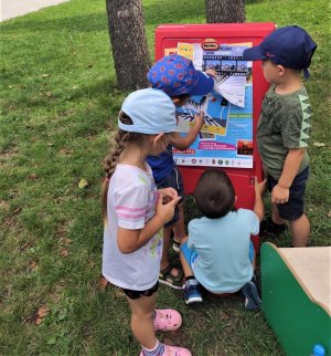 troje przedszkolaków przygląda się plakatom promującym bezpieczeństwo w czasie wakacji