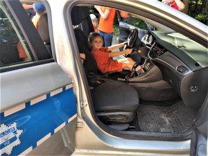 mała dziewczynka siedzi za kierownicą policyjnego radiowozu