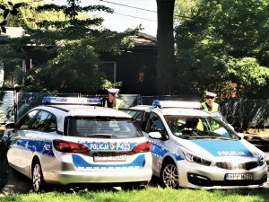 policjanci wsiadają do radiowozów zaparkowanych przed budynkiem komendy
