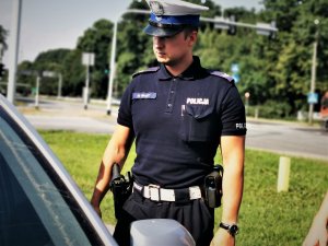 policjant ruchu drogowego stoi przy samochodzie, w tle droga krajowa numer 81 w Orzeszu