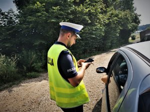 policjant ruchu drogowego stoi obok samochodu w trakcie drogowej kontroli