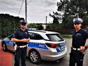 policjanci drogówki stojący przed radiowozem