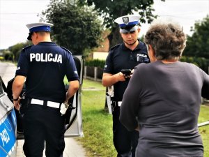 policjanci drogówki oraz starsza kobieta stojąca przy swoim rowerze