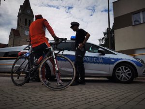 policjanci drogówki, za nimi radiowóz, obok nich stoi rowerzysta