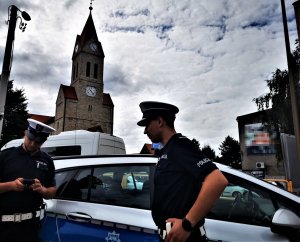 policjanci drogówki, za nimi radiowóz, w tle kościół w Orzeszu