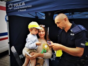 policjant przekazuje odbalskowe elementy dziecku, które jest w towarzystwie