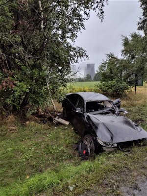 leżący w rowie samochód marki bmw, w tle kominy