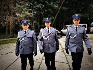 trzech policjantów idzie obok siebie, teren placu przy kościele