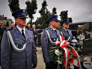 trzech policjantów niesie wieniec pod pomnik poległych mundurowych IIRP, w tle inni uczestnicy uroczystości