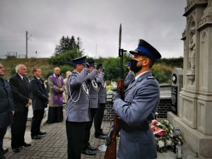 trzech umundurowanych policjantów oddaje hołd poległym mundurowym. Obok nich policjant asysty honotowej. Scena ma miejsce na cmentarzu w Ornontowicach.