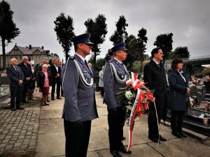 trzech policjantów niesie wieniec pod pomnik poległych mundurowych IIRP, w tle inni uczestnicy uroczystości