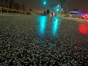 zbliżenie na asfalt, w tle pracujący przy eksperymencie policjanci