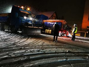 dwie pługopiaskarki na drodze krajowej, przed nimi policjant oraz mężczyzna w ciemnym ubraniu