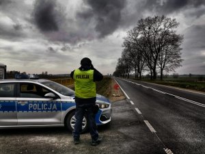 droga, policyjny radiowóz, policjant patrzący przez lornetkę