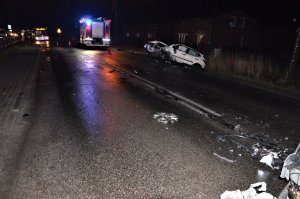 ulica, w rowie rozbity samochód, w tle wóz straży pożarnej oraz autobus miejski